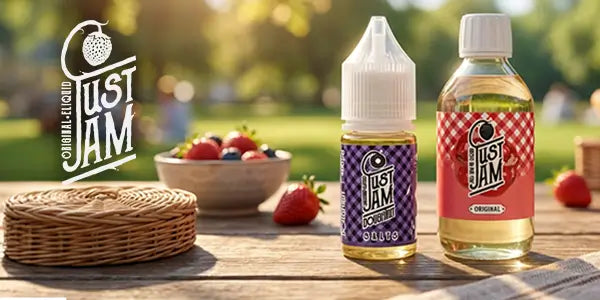 Just Jam original e-liquid display featuring strawberry jam nicotine salt and shortfill bottles on a rustic wooden table with fresh berries and a picnic basket outdoors.